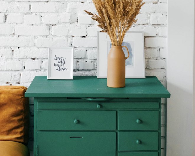 A green drawer with a picture frame and a brown vase on top